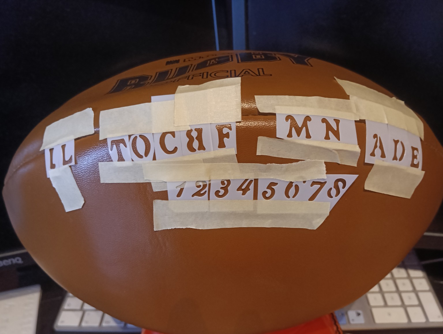 Stencil delle lettere e dei numeri fissati con il nastro sul pallone, prima della colorazione